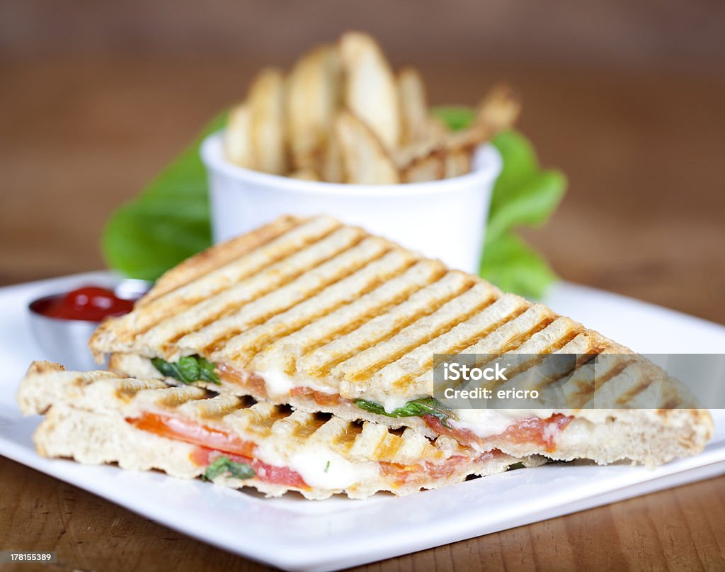 Grilled caprese sandwich with fried potatoes Grilled caprese sandwich with fried potatoes and ketchup on a plate American Culture Stock Photo