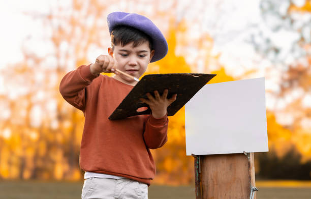 istock boy kid is painting in park on old easel using oil colors. 1781555364