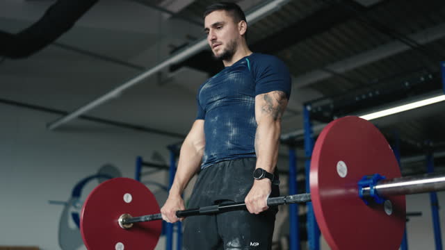 Determined Young Male Athlete in Sportswear Lifting Barbell During Workout at Gym