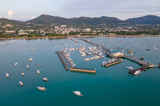 Aerial drone view of Chalong Pier in Phuket, Thailand. Many boats, yachts, catamarans and speed boats moored at the pier platform of Ao Chalong Bay, one of centers to travel around Andaman Sea.