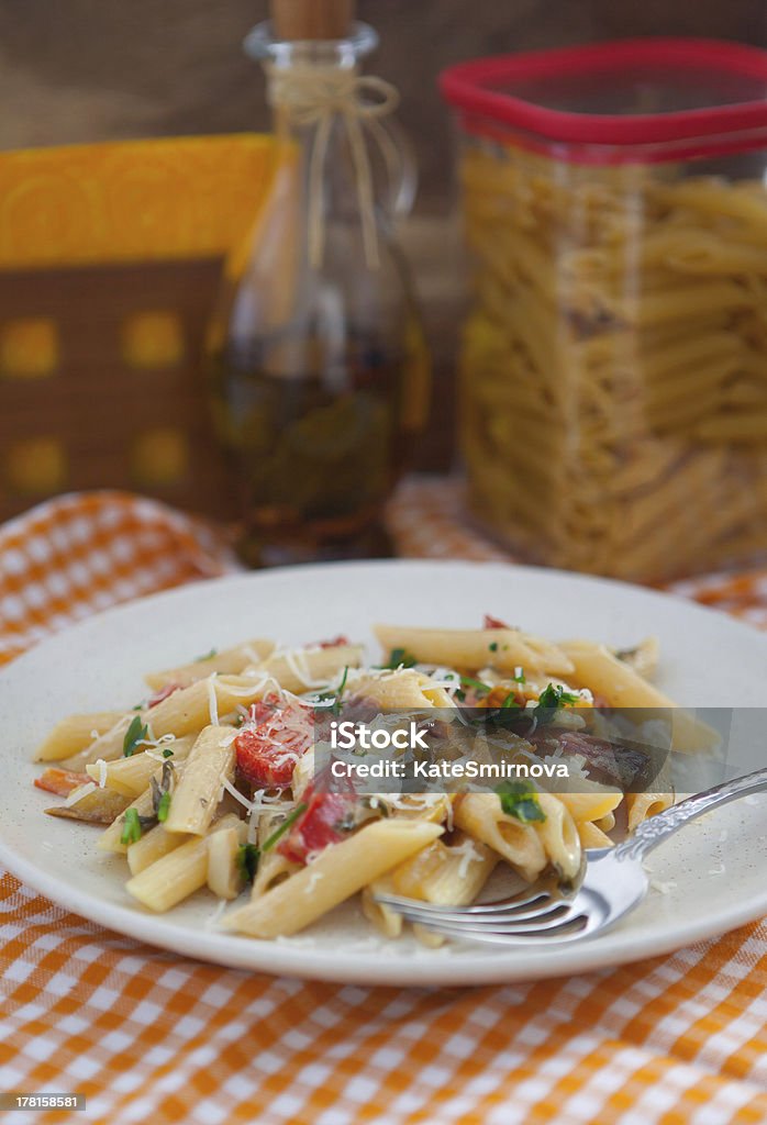 Peppered pasta "Peperonata pasta on a checkered tablecloth on the background of wooden boards, olive oil and dry pasta" Cooking Oil Stock Photo