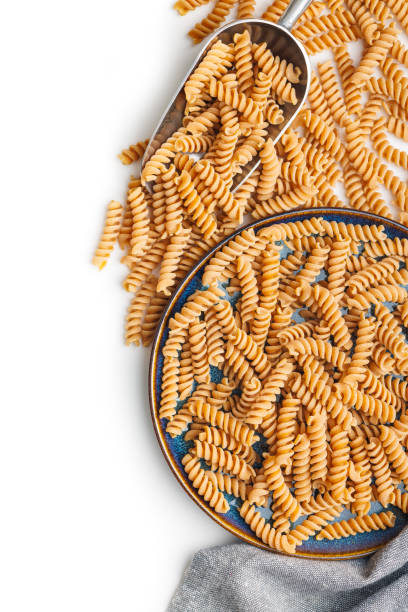 istock Raw whole grain fusilli pasta. Uncooked pasta on plate isolated on white background. 1781605779