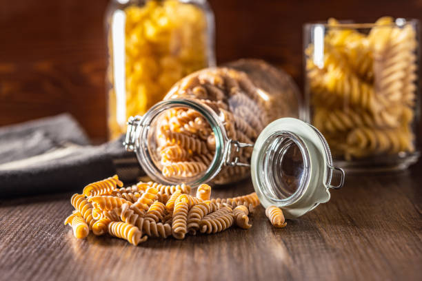 istock Raw whole grain fusilli pasta. Uncooked pasta on wooden table. 1781611784