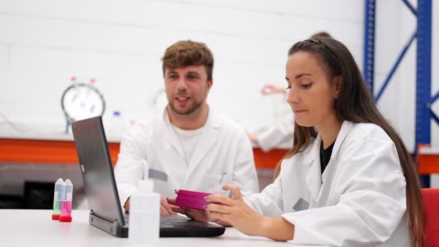 Chemistry workers talking and working on laptop
