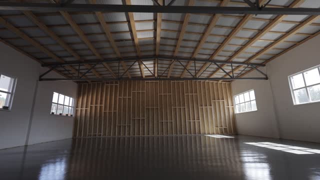 Spacious empty well-lighted hall for celebrating with wooden details. Large space under roof with windows and shiny concrete floor for holding events indoors. Concept of building and holidays.