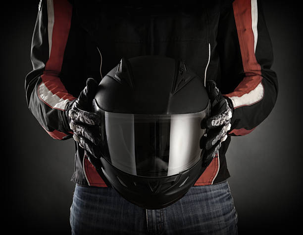 Man holds black motorcycle helmet with visor stock photo