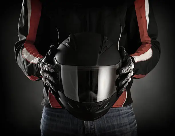 Photo of Man holds black motorcycle helmet with visor