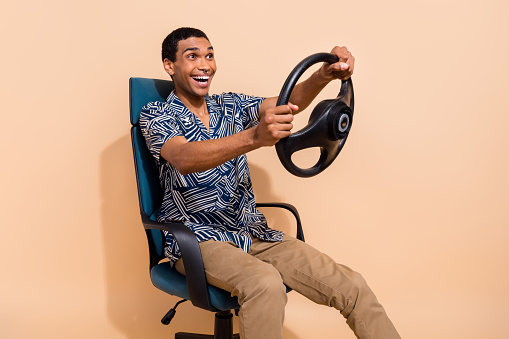 Photo of sweet handsome man wear print shirt driving car fast smiling isolated beige color background.