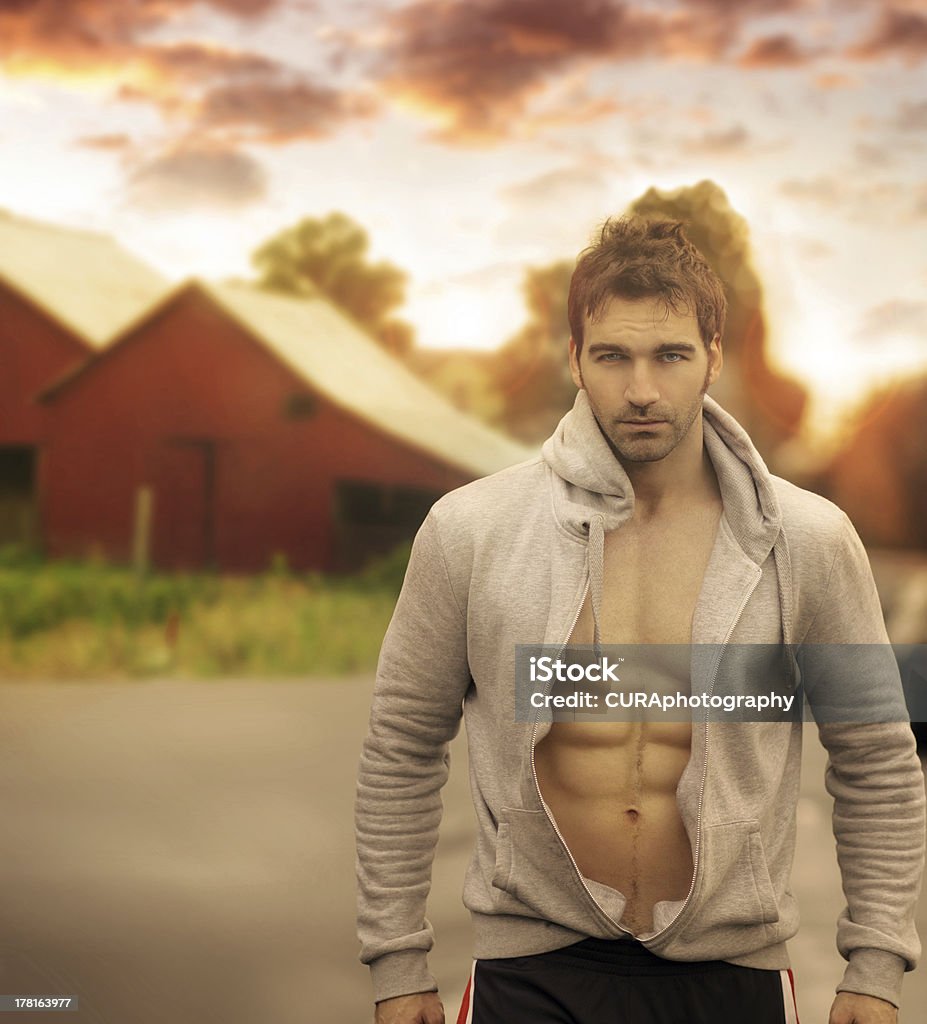 Outdoor man Beautiful male model with great body in romantic rustic outdoor setting with red barn in background and moody sky above Abdominal Muscle Stock Photo