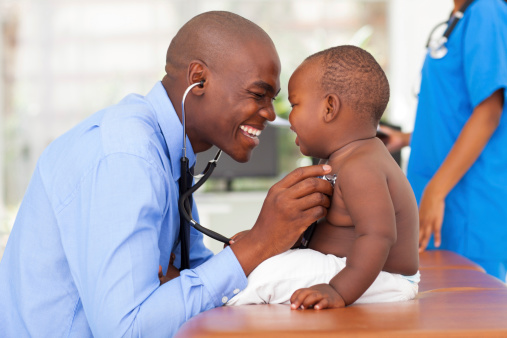 happy african male doctor examining baby boy with female nurse on background