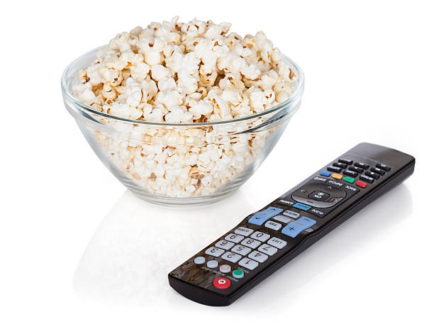 Close-up Of Remote Control And Popcorn Close-up Of Remote Control And Bowl Of Popcorn Over White Background popcorn snack bowl isolated stock pictures, royalty-free photos & images