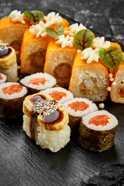 istock Set of different sushi rolls on a black board. Assorted Japanese sushi with salmon, eel, shrimp 1781656977