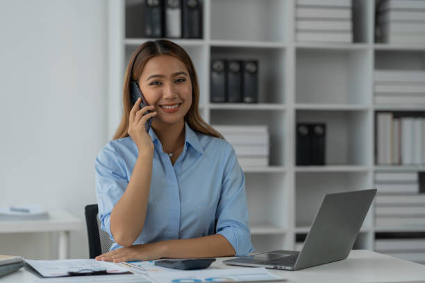 istock Happy Asian businesswoman talking on the phone and smiling while sitting at work using smartphone to talk. Contact via online application, concept of management 1781660379