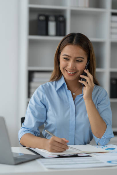 istock Happy Asian businesswoman talking on the phone and smiling while sitting at work using smartphone to talk. Contact via online application, concept of management 1781662109