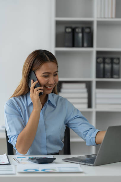 istock Happy Asian businesswoman talking on the phone and smiling while sitting at work using smartphone to talk. Contact via online application, concept of management 1781663200