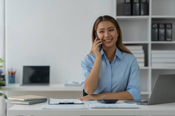 istock Happy Asian businesswoman talking on the phone and smiling while sitting at work using smartphone to talk. Contact via online application, concept of management 1781671384