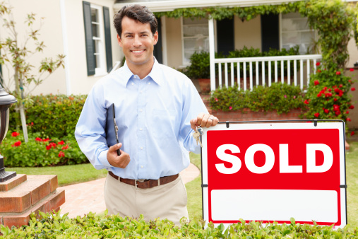 Real estate agent at work holding clipboard smiling at camera