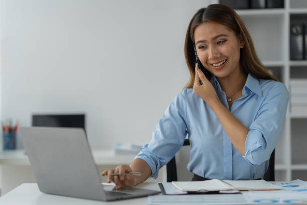 istock Happy Asian businesswoman talking on the phone and smiling while sitting at work using smartphone to talk. Contact via online application, concept of management 1781677379