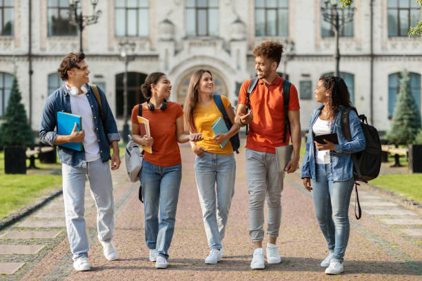 A group young adults walking across a college campus with a backpack, smiling.