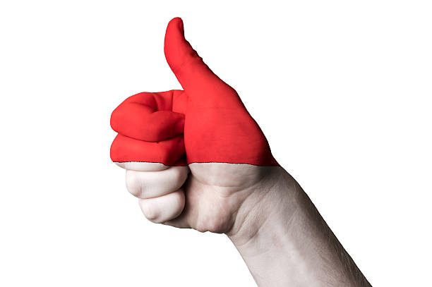 Hand with thumb up gesture in colored indonesia national flag as symbol of excellence, achievement, good, - for tourism and touristic advertising, positive political, cultural, social management of country