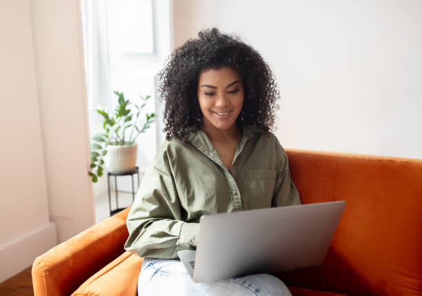 istock Smiling Black Young Lady Freelancer Using Laptop On Sofa Indoor 1781725630
