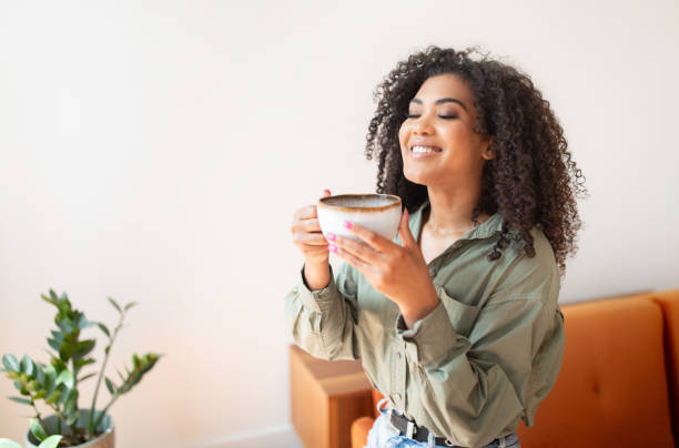 istock Glad young black lady drinks favorite tea in living room 1781725687