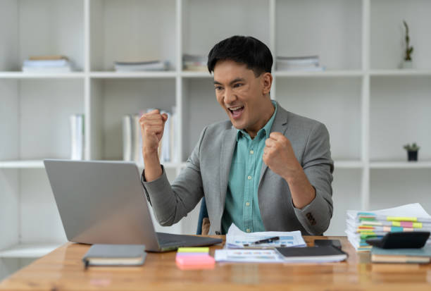 istock confident young businessman Happy smart gesture excited with laptop computer and raised arms to celebrate happy financial business success startup business ideas. 1781728507