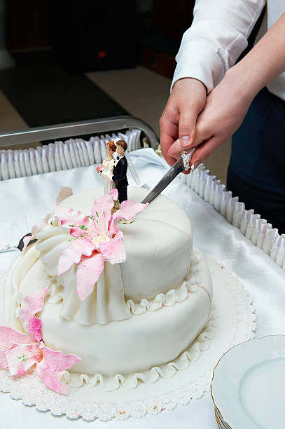 istock Groom and bride cuts the wedding cake with pink flowers 178172859