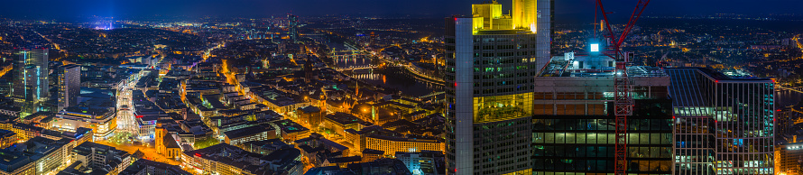 Aerial panoramic view over the central business district skyscrapers and warm lights of the streets of Frankfurt am Main, Germany’s vibrant financial centre.