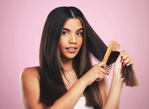 Portrait, woman and brush hair in studio for smooth texture, shine and keratin treatment on pink background. Natural beauty, face and model with comb tools for aesthetic hairstyle with growth shampoo