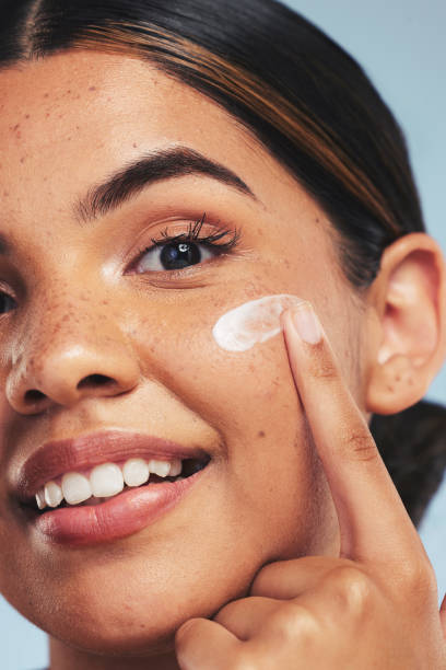 Face, skincare cream and portrait of woman for aesthetic shine, dermatology and makeup cosmetics on studio background. Closeup, happy model and facial sunscreen lotion for self care, beauty and glow rostro, crema para el cuidado de la piel y retrato de mujer para brillo estético, dermatología y cosméticos de maquillaje en fondo de estudio. primer plano, modelo feliz y loción de protección solar facial para el cuidado personal, la belleza y el bri