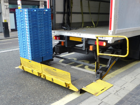 A truck tail lift with some crates ready to be loaded onto the truck.