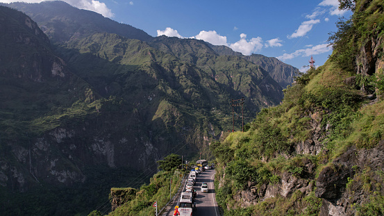 Rudraprayag,India-September 12,2023:A beautiful view of a scary mountain highway with slow-moving traffic and mountain peaks during the spring morning