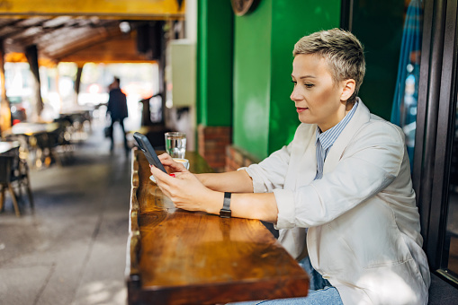 A business woman relaxes in a coffee shop during a coffee break and checks her finances  using a mobile app