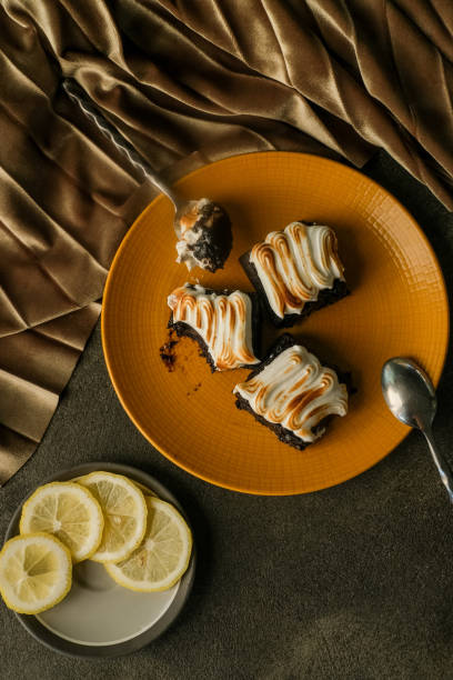 istock Lemon brownies with cream and egg white meringue topping on yellow plate with dramatic shadows on background with velvet fabric background 1781872784