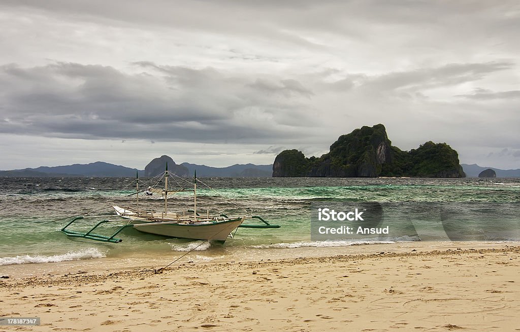 Łódka siedzenia przy shore w burzliwe pogoda w obfitym chmury - Zbiór zdjęć royalty-free (Azja)