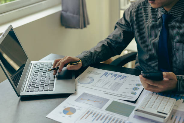 istock Young Asian businessman working with laptop, checking graphs, company budget reports, production control. Operational inspection cost plus price Close-up pictures 1781880324