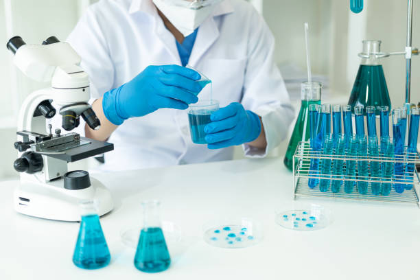 istock Doctor in mask examining DNA molecule in chemistry lab with scientist examining liquid sample with microscope in chemistry lab Researcher working with sample 1781880381