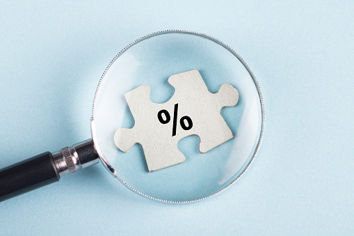 Percentage sign on puzzle piece with magnifying glass