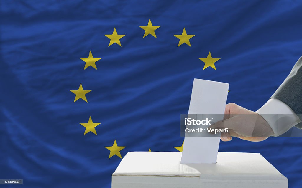 Homem colocando a mão na caixa de voto em eleições da UE - Foto de stock de Bandeira da Comunidade Européia royalty-free