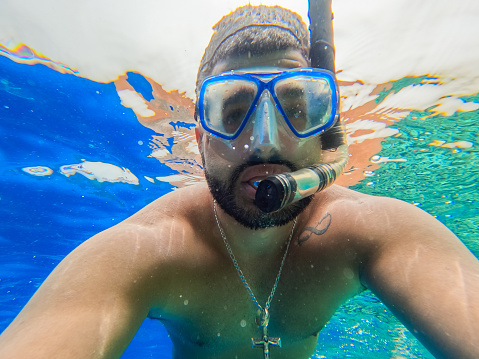 Handsome young man taking a selfie while snorkeling in the Red sea in Hurghada in Egypt.