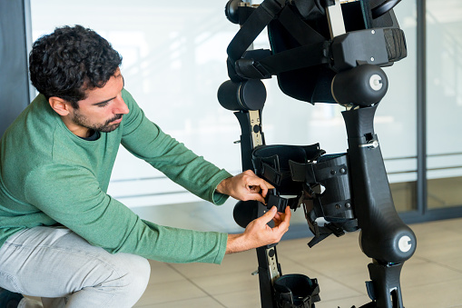 Mechanical exoskeleton engineer checking the mechanisms before the arrival of patients. Physiotherapy in a modern hospital: Robotic skeleton. Physiotherapy Rehabilitation Scientists, Engineers and Physicians