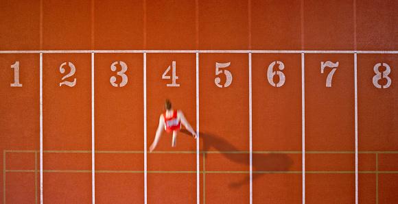 Blurred motion of male athlete reaching finishing line on running track.