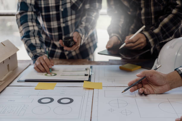 istock Engineer points to building on blueprint and uses laptop to draw building design project in office Image engineer concept of engineer meeting for architectural project Work with partners 1781918619