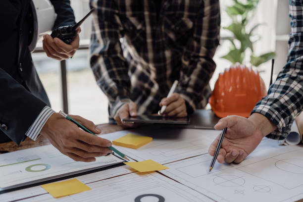 istock Engineer points to building on blueprint and uses laptop to draw building design project in office Image engineer concept of engineer meeting for architectural project Work with partners 1781918621