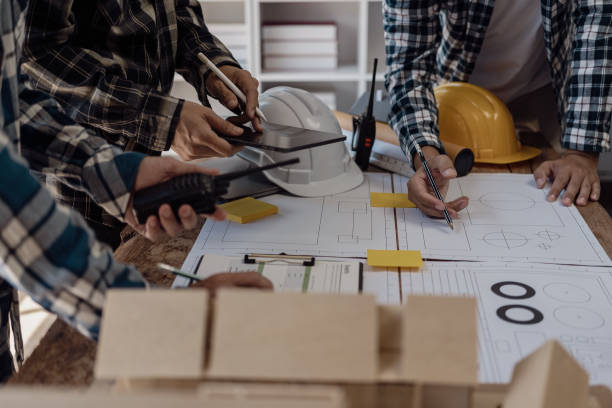 istock Engineer points to building on blueprint and uses laptop to draw building design project in office Image engineer concept of engineer meeting for architectural project Work with partners 1781918623