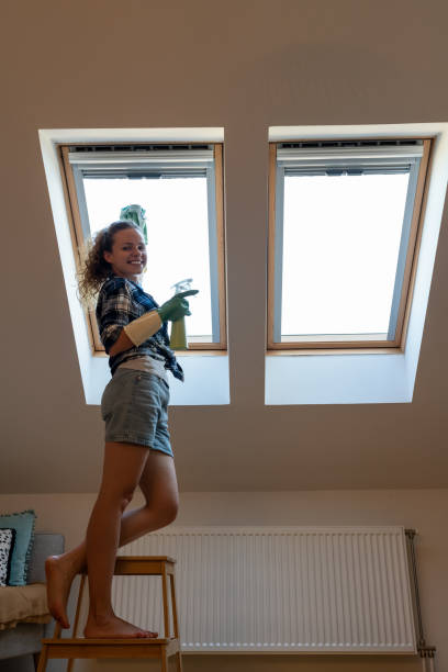 istock Brunette woman cleaning roof light window at home using squeegee. 1781991938