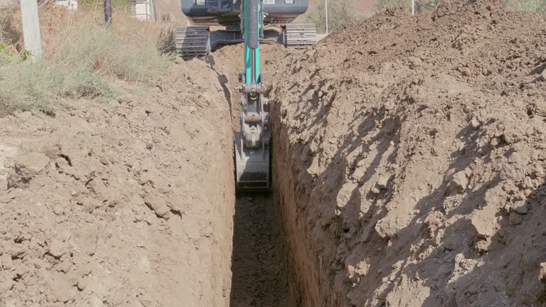 A tractor digs a trench in the ground. Construction work and communications