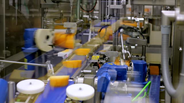 Machine slicing pieces of yellow cheese in a food factory