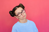 young woman in blue clothes, wearing glasses is very upset, looking sadly at the camera, tilting her head to the side.